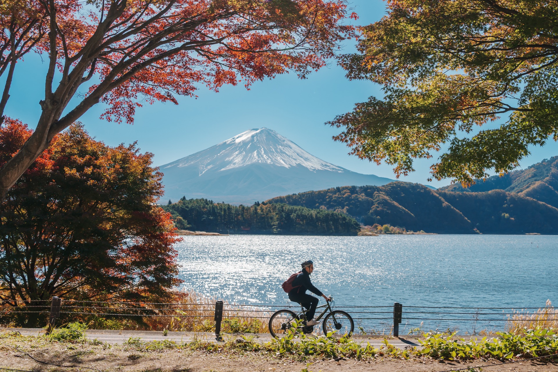 Ciclista pedaleando junto al lago Kawaguchi con el Monte Fuji nevado al fondo