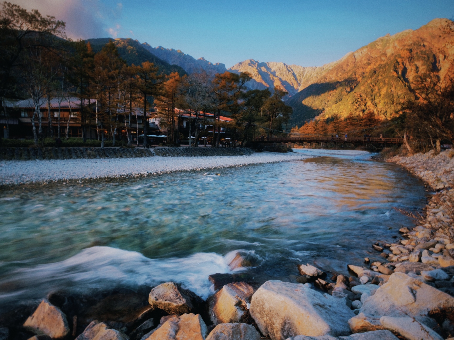 Río cristalino al atardecer en Kamikochi rodeado de montañas