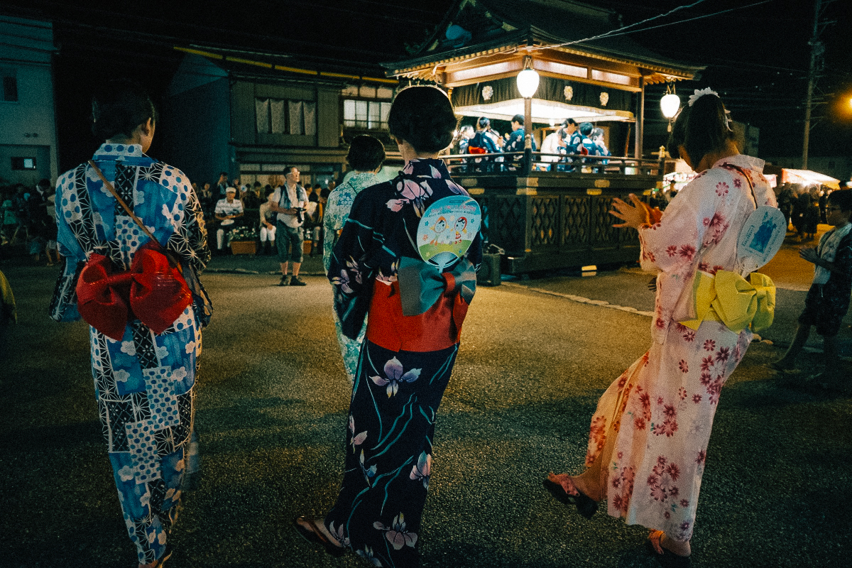 Varias personas con yukata durante un matsuri participan en un bon odori