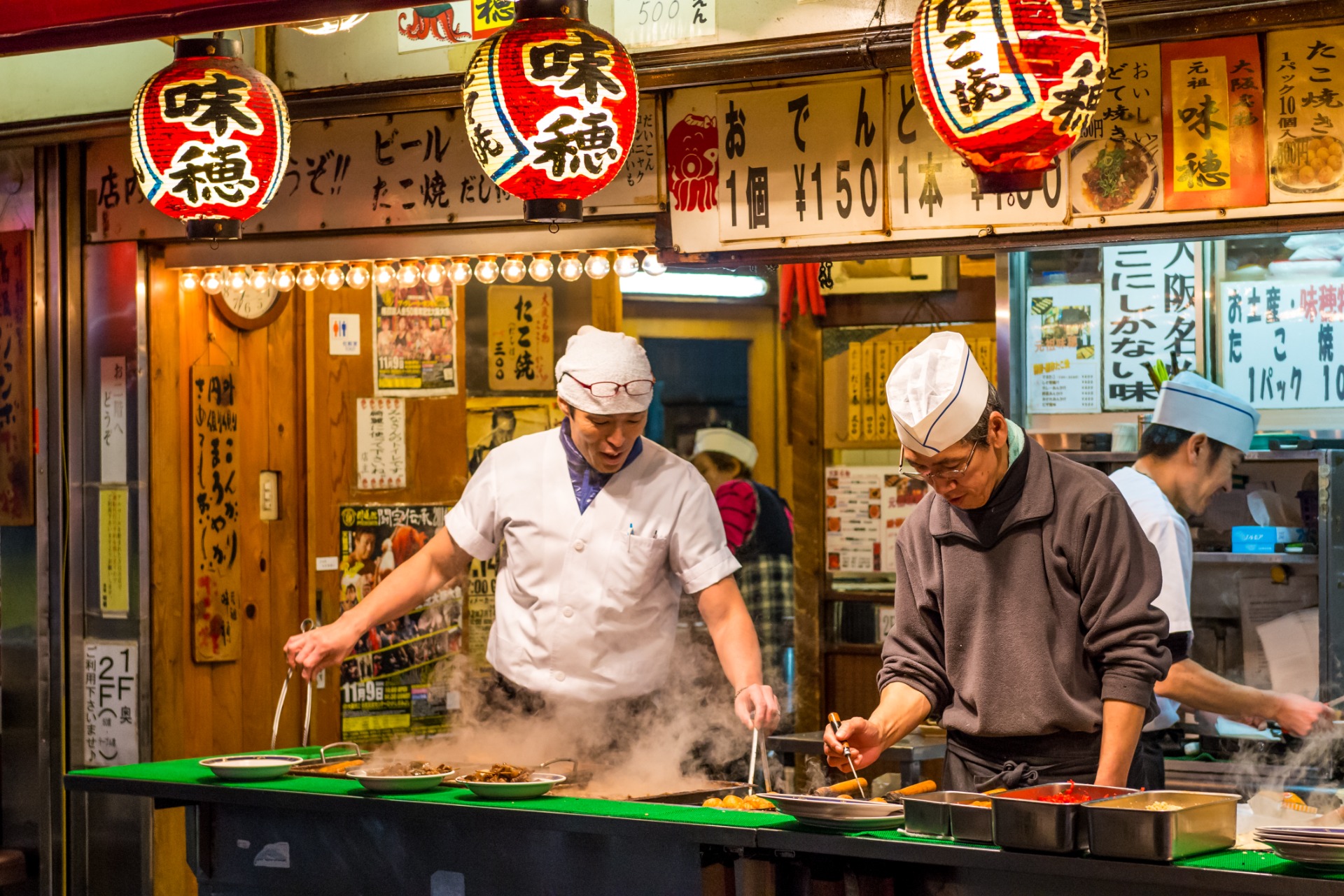 Cocineros japoneses preparando platos callejeros en un yatai
