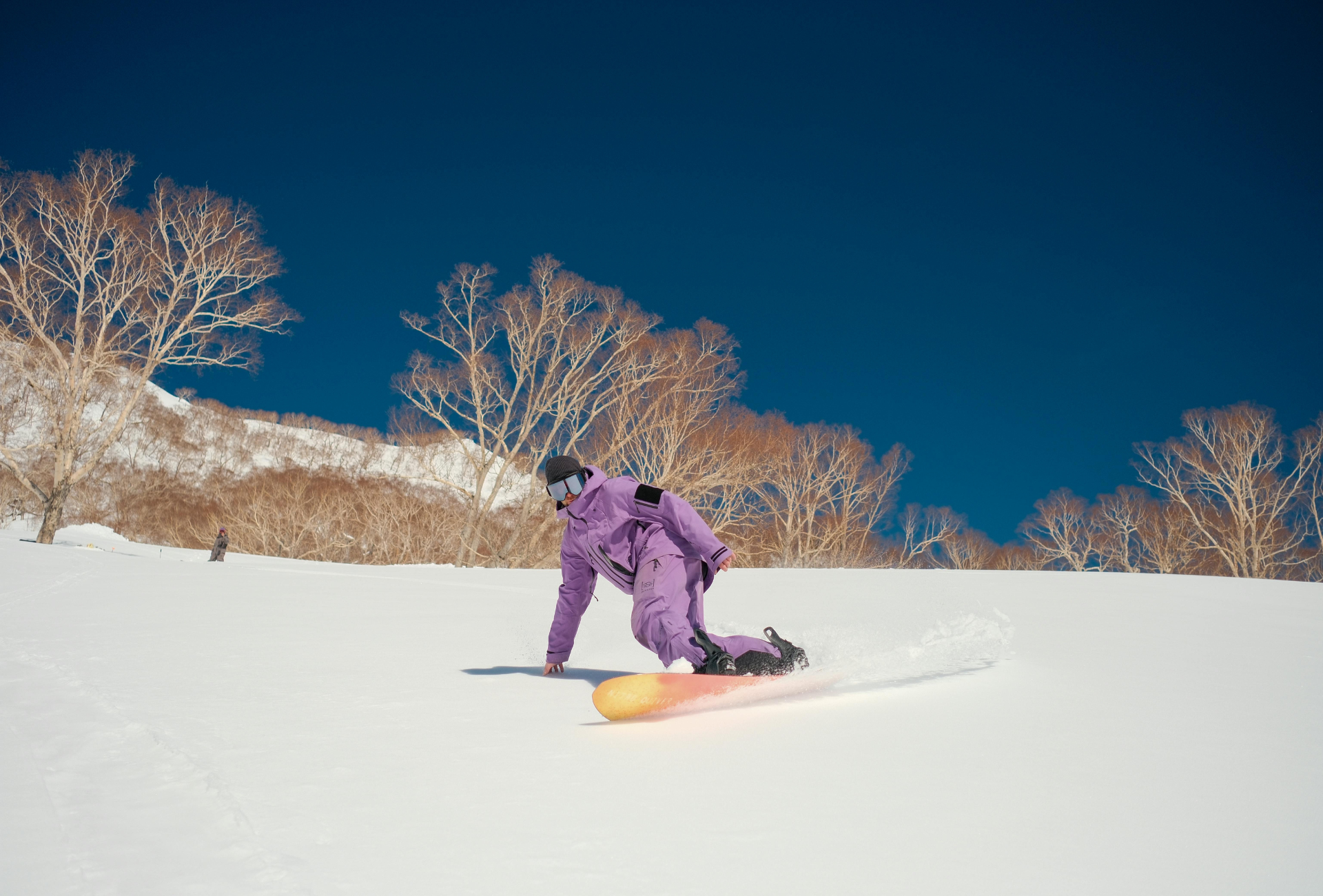 Snowboarder descendiendo por una ladera nevada en Japón