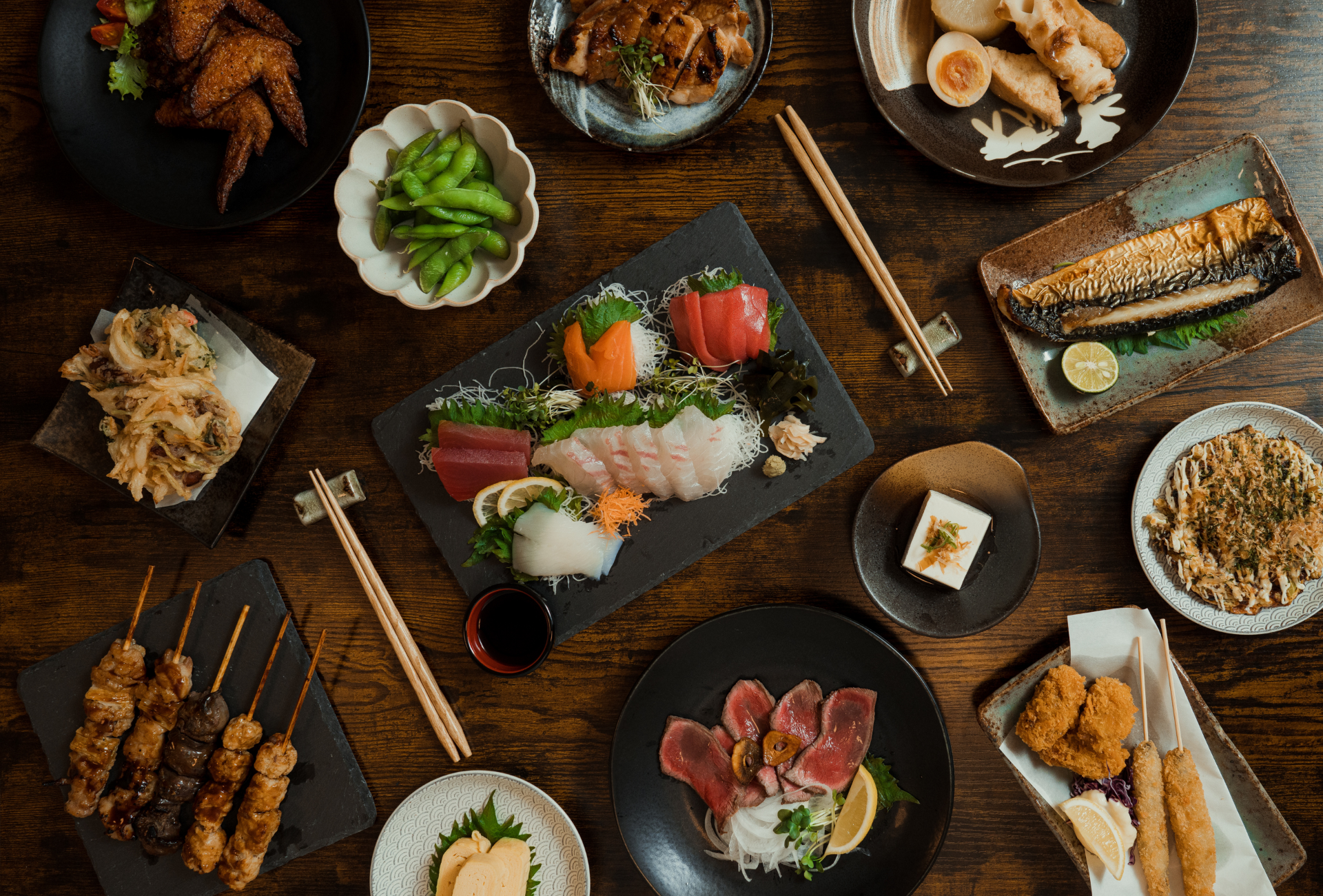 Cena tradicional japonesa con sashimi, yakitori y platos típicos