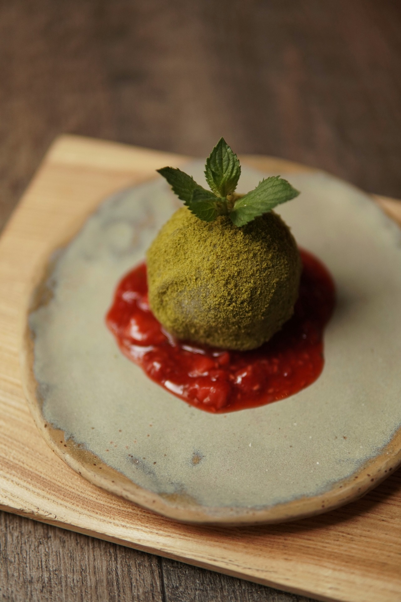 Daifuku mochi cubierto de polvo de matcha y servido con coulis de fresa