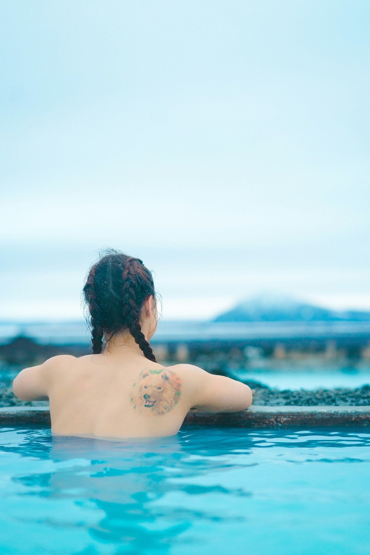 Mujer con un tatuaje en la espalda en una piscina termal exterior