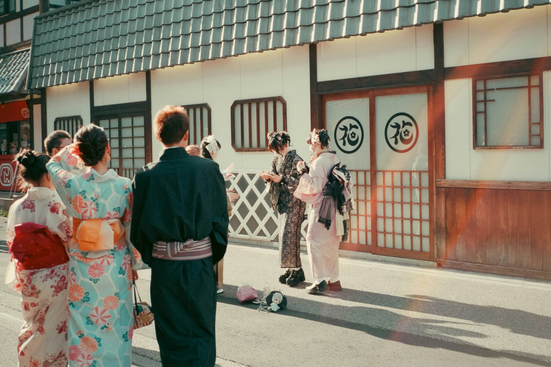 un grupo de personas vestidas de kimono consulta el móvil en la calle
