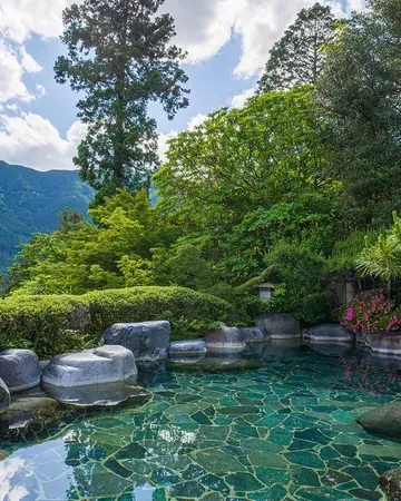 Baño termal al aire libre entre rocas y jardín del ryokan Yunoshimakan, en Gero Onsen
