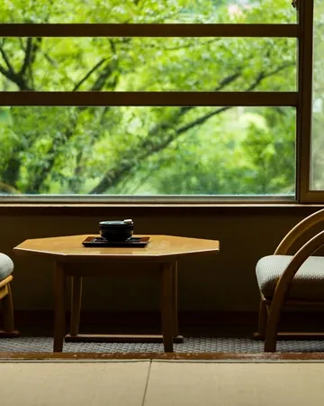 Sillones y mesa de té junto al ventanal abierto al bosque en una habitación del ryokan Kajikaso, Hakone