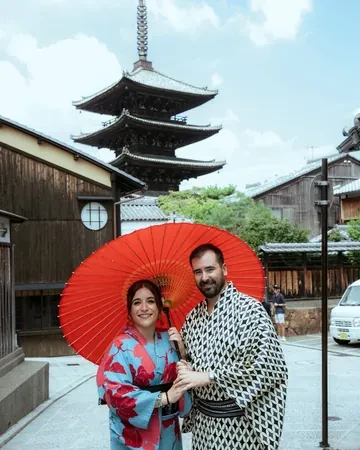Rafael y Fátima, clientes de Japonal, en kimono con un paraguas rojo junto a la pagoda Yasaka, en Kioto