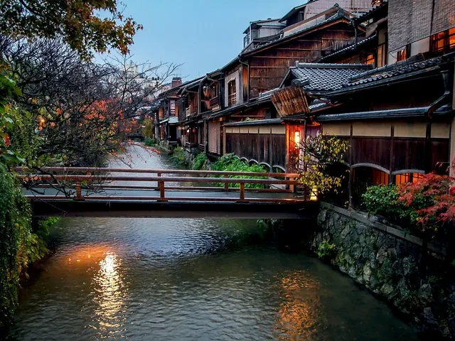 Canal Shirakawa en el barrio de Gion al anochecer, con casas de madera y un puente de piedra, Kioto