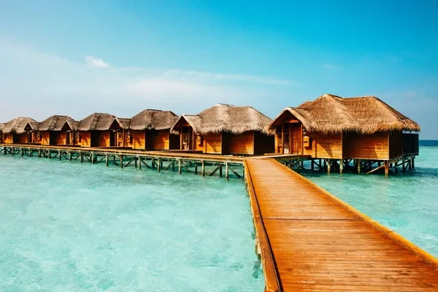 Villas sobre el agua con tejado de paja y pasarela de madera en un resort de Maldivas