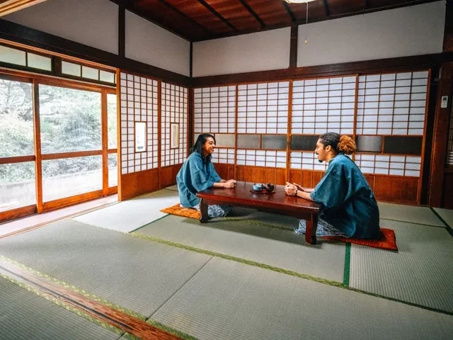 Pareja en yukata tomando té en la mesa baja de una habitación de tatami de un ryokan